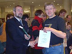 Hugo Schulz überreicht eine Urkunde mit einem kleinen Präsent an Siegmund Braun
